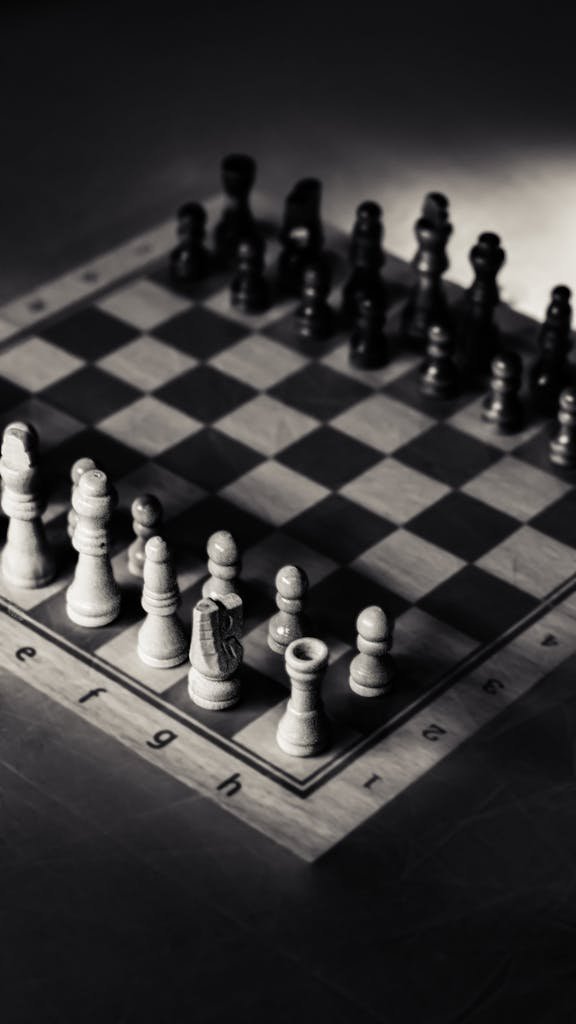 A dramatic black and white photo of a chessboard with all pieces set for a classic game.