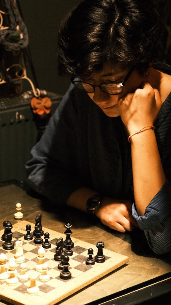 A focused woman contemplating her next move in a chess game.