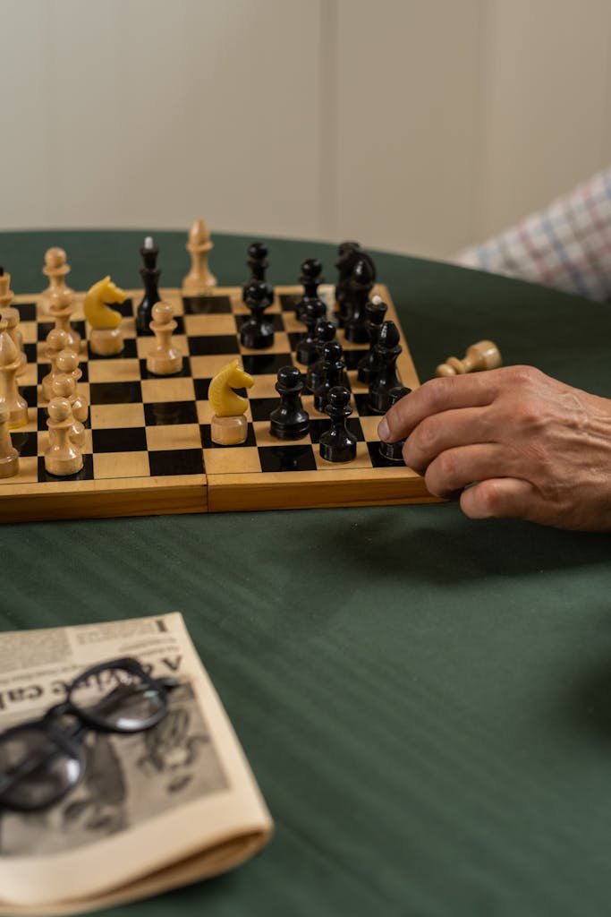 An intense moment in a chess game with hands moving a piece on a wooden board.