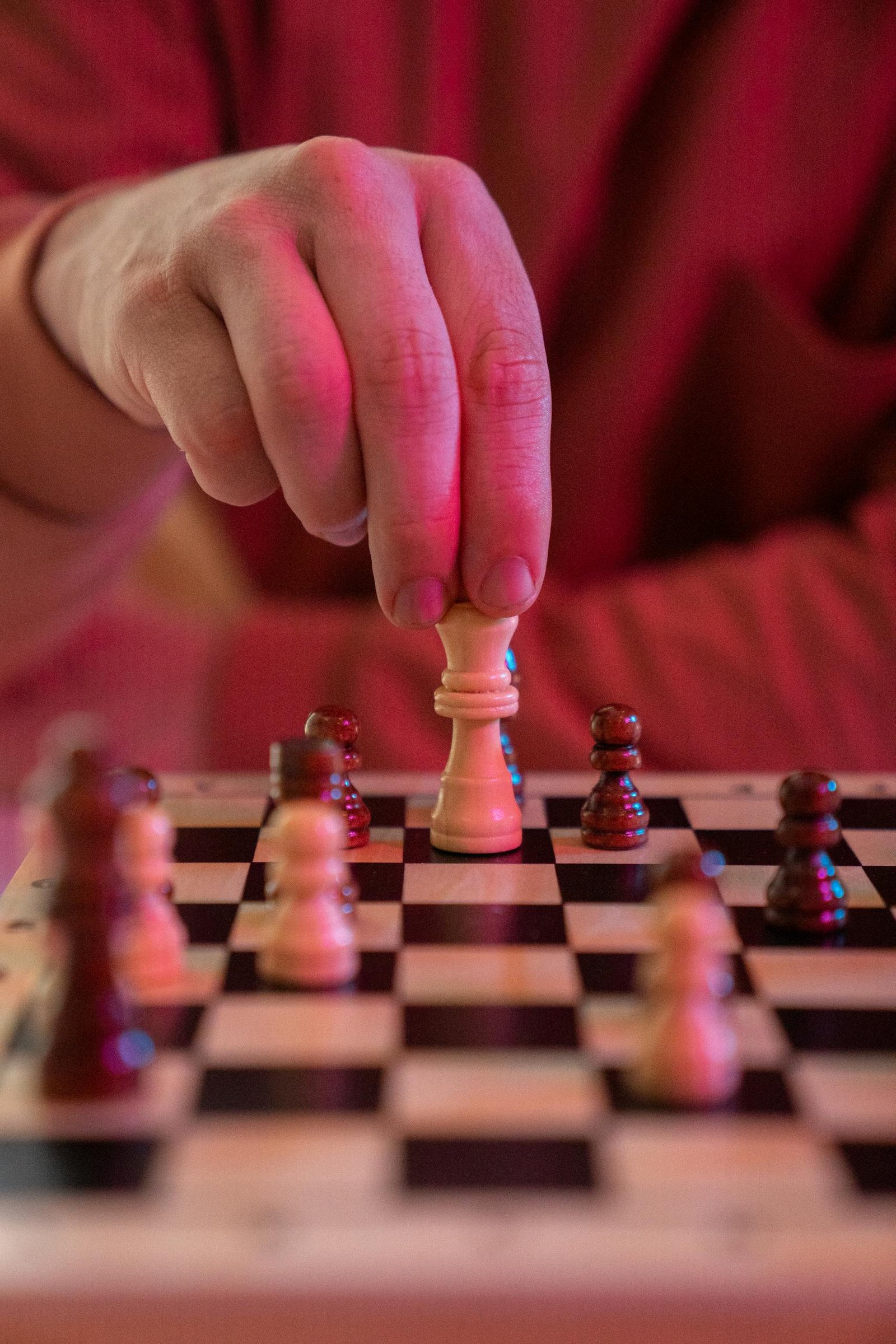 Close-up of a hand moving a chess piece, symbolizing strategy and focus.